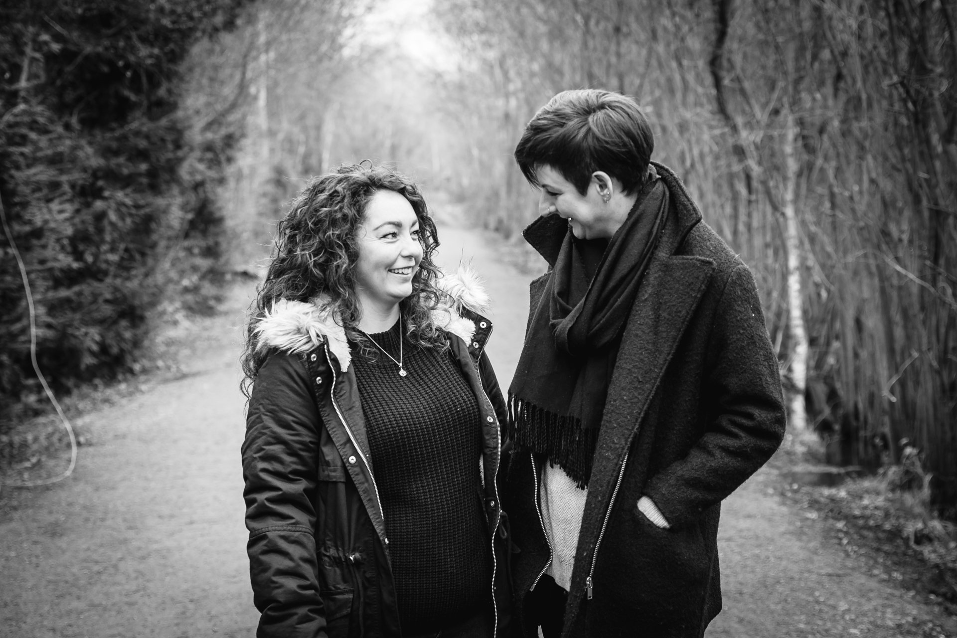 Two gorgeous ladies smiling during their engagement shoot in a woodland setting in Kent