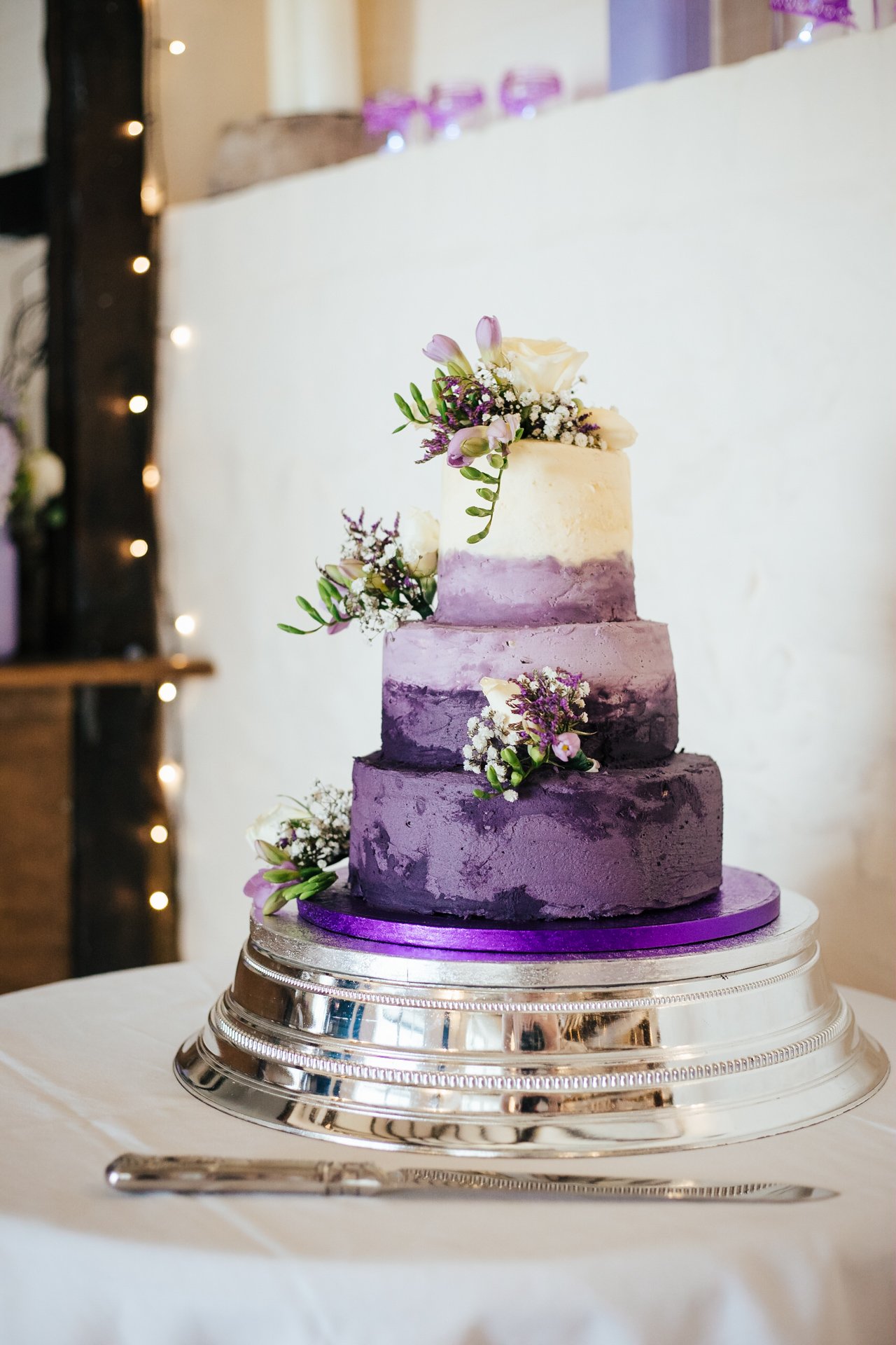 Stunning three tier wedding cake, rustic texture adorned with flowers