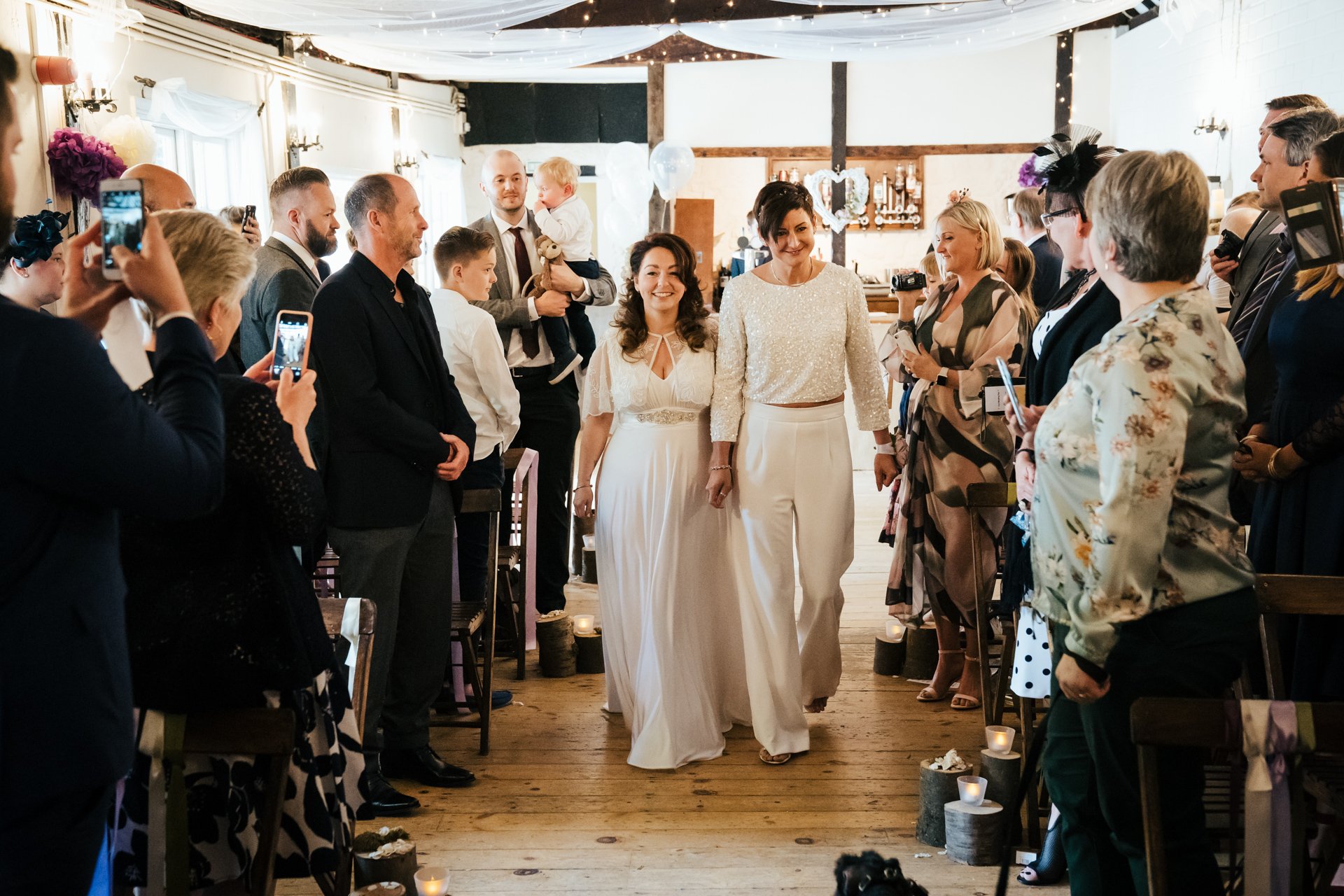 Two Brides walking down the aisle together for the wedding ceremony at The Bull Hotel, Kent