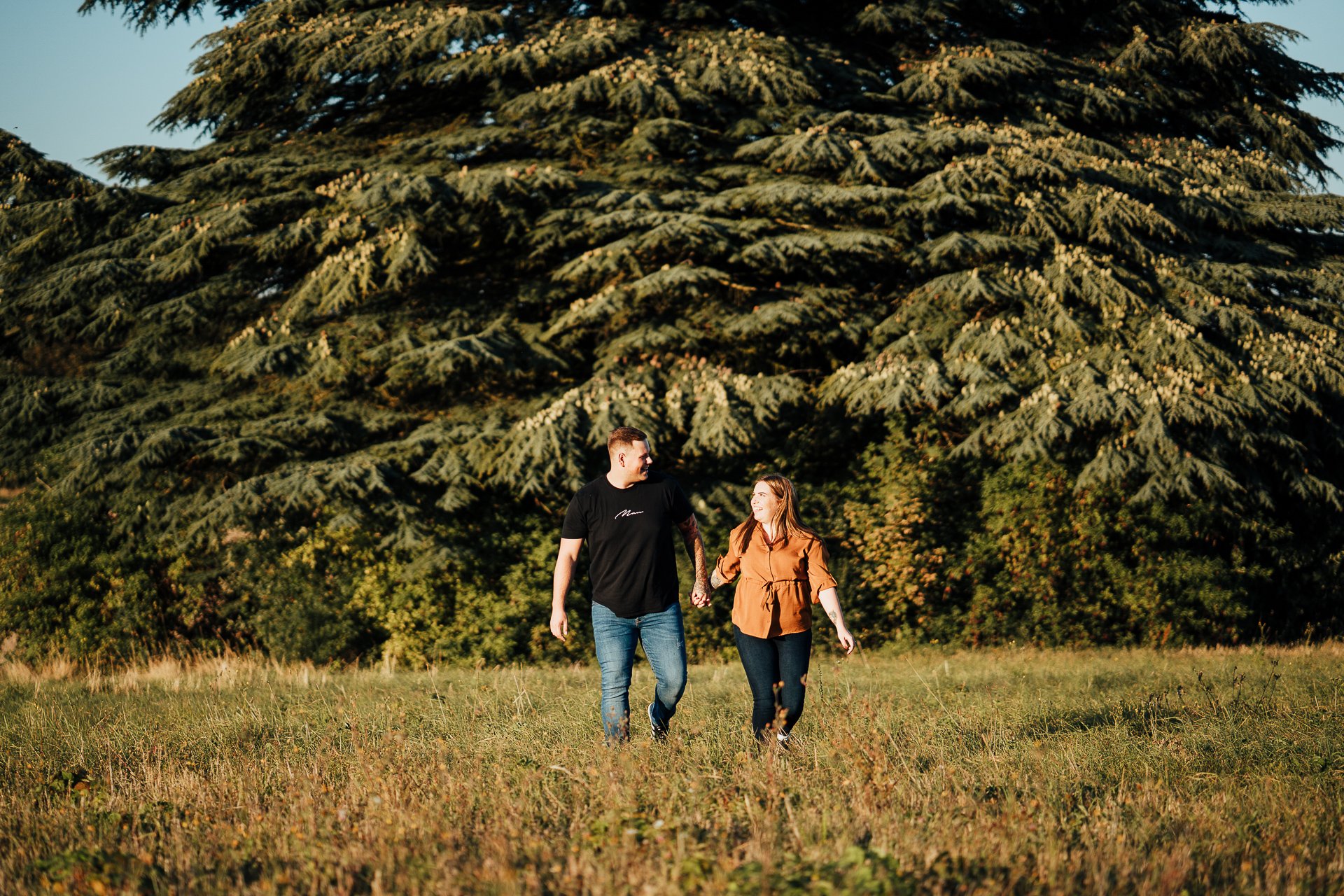 Engaged couple looking at each other during their autumnal sunset engagement shoot at Lullingstone Country Park, Kent