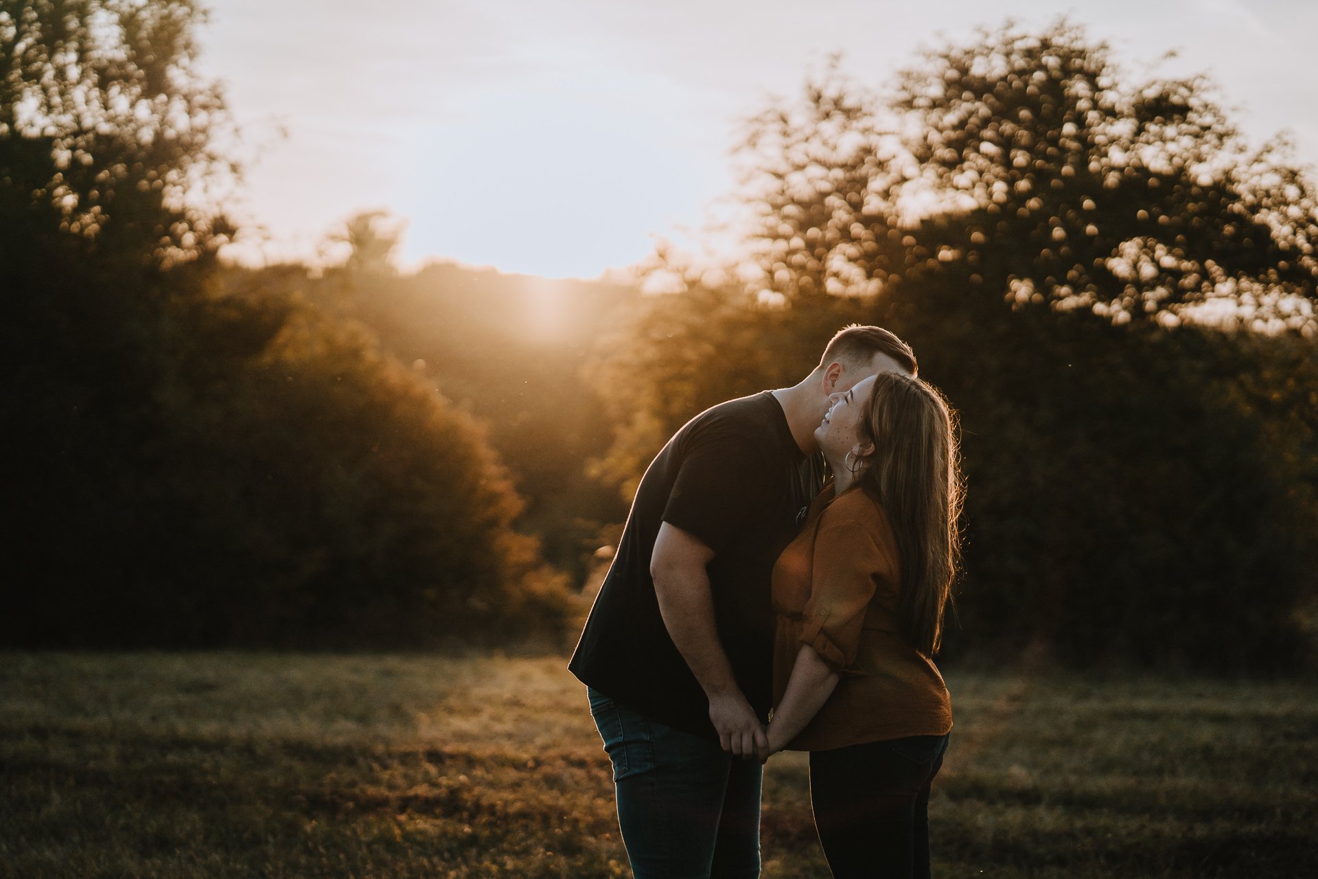 Engaged couple smiling at each other in their sunset pre wedding shoot at Lullingstone Country Park, Kent