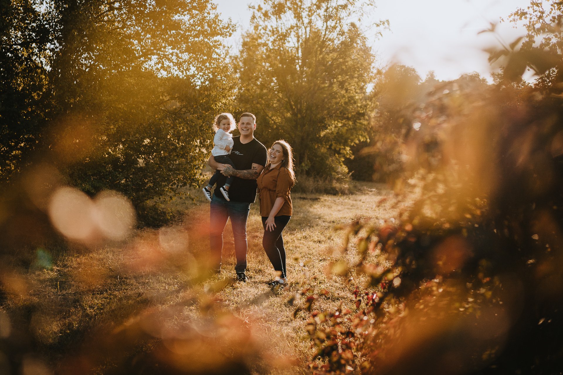 Engaged couple and their daughter in warm autumn evening light at Lullingstone Country Park Kent