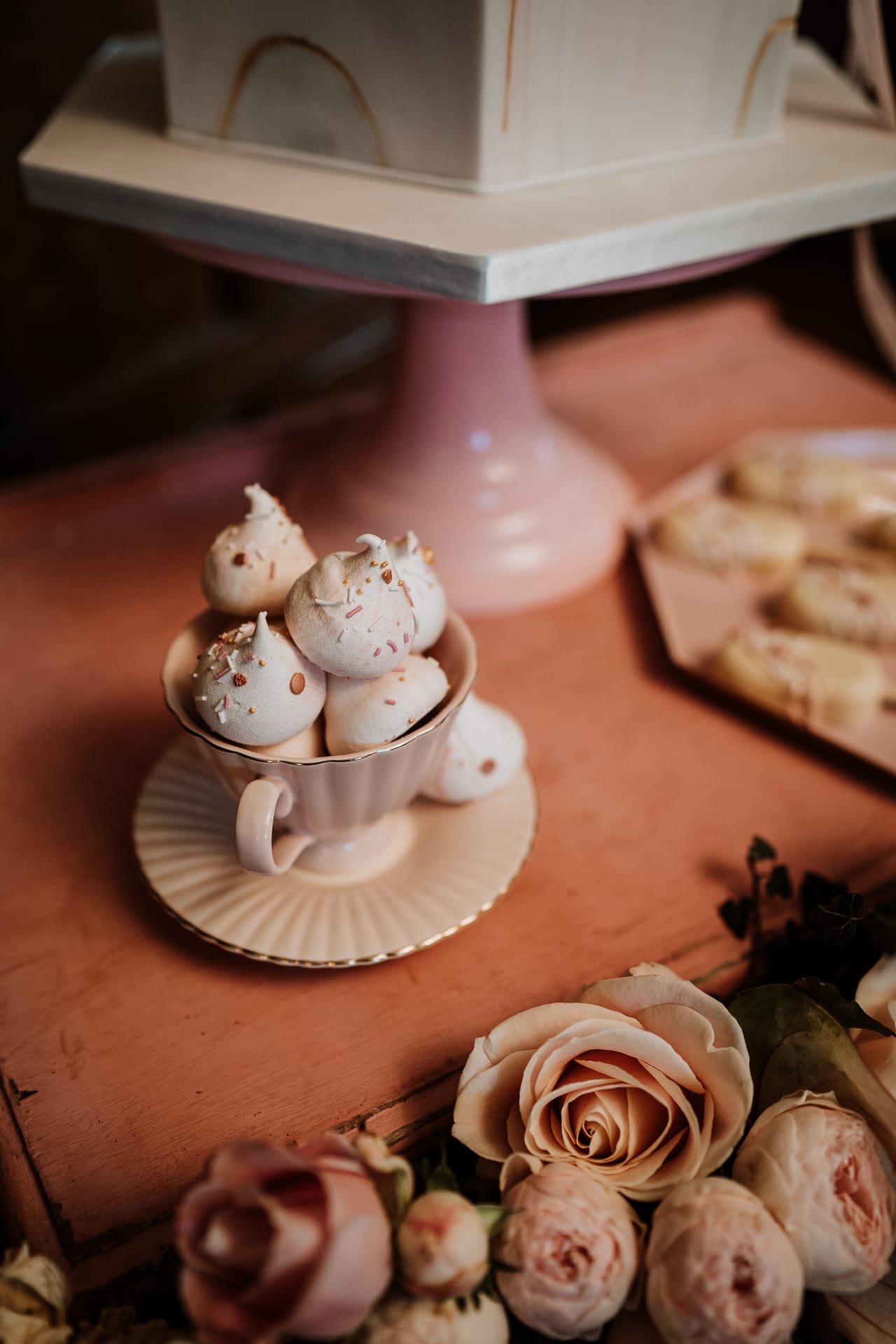 Meringue kisses in pink cup on dessert table