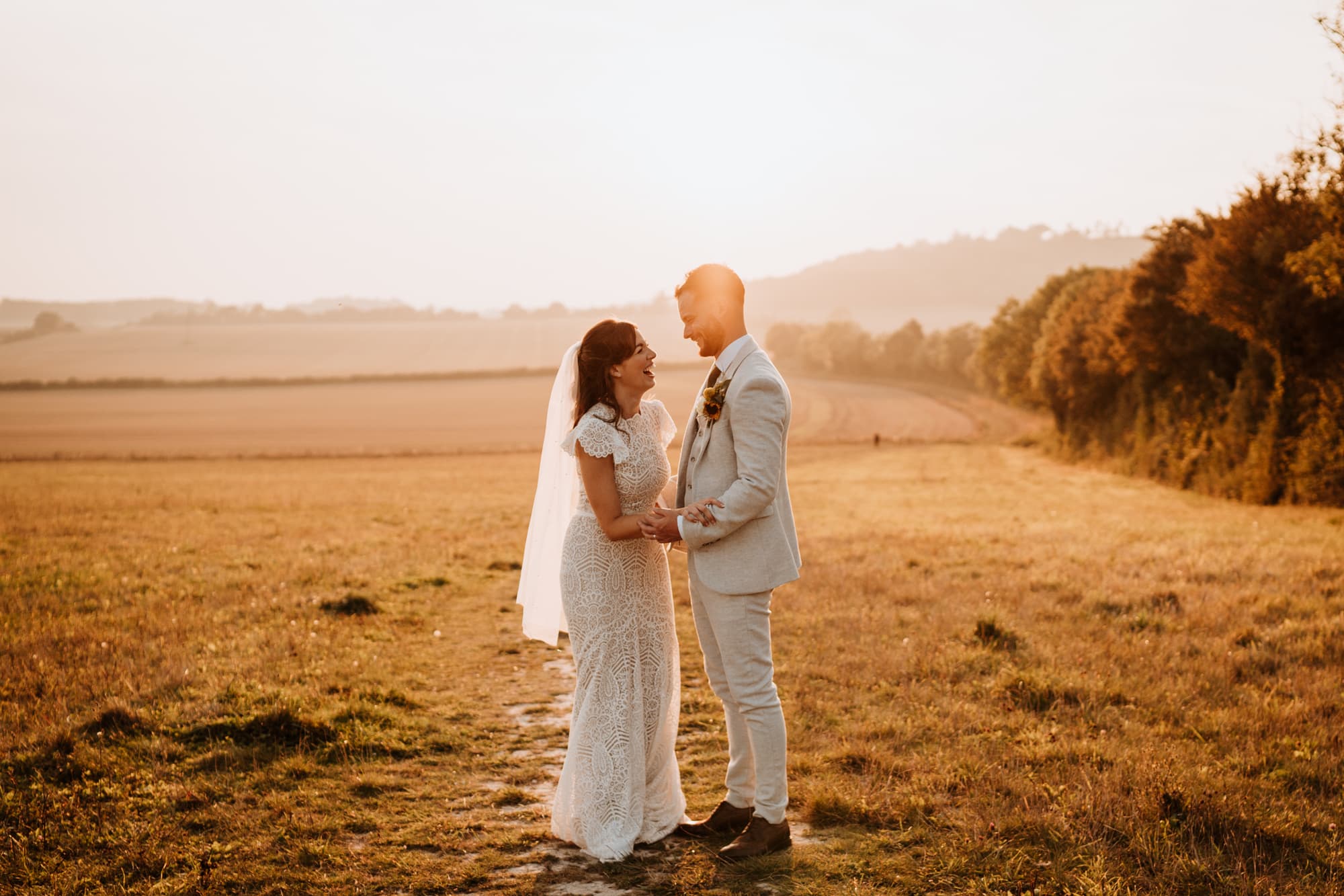 Bride and groom laughing together at sunset in happy relaxed portraits