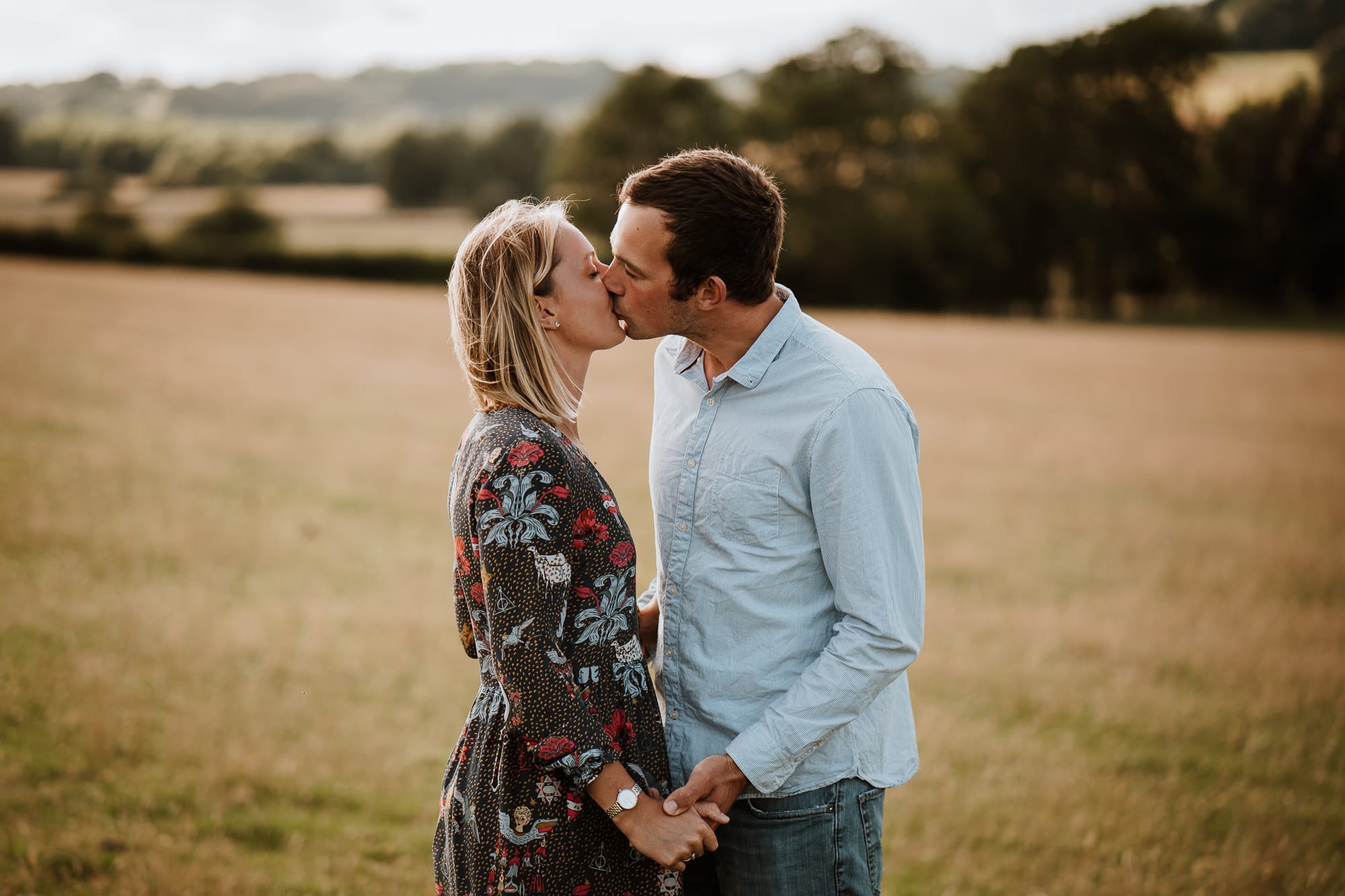 Couple kissing and holding hands in the countryside during their engagement photography