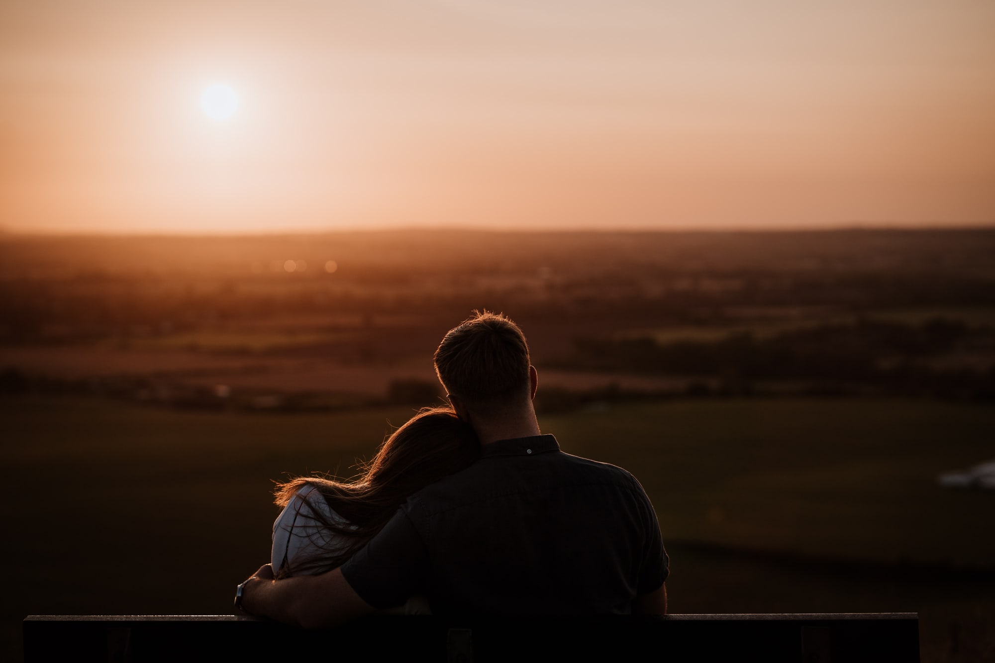 Couple watch the sunset together during engagement shoot