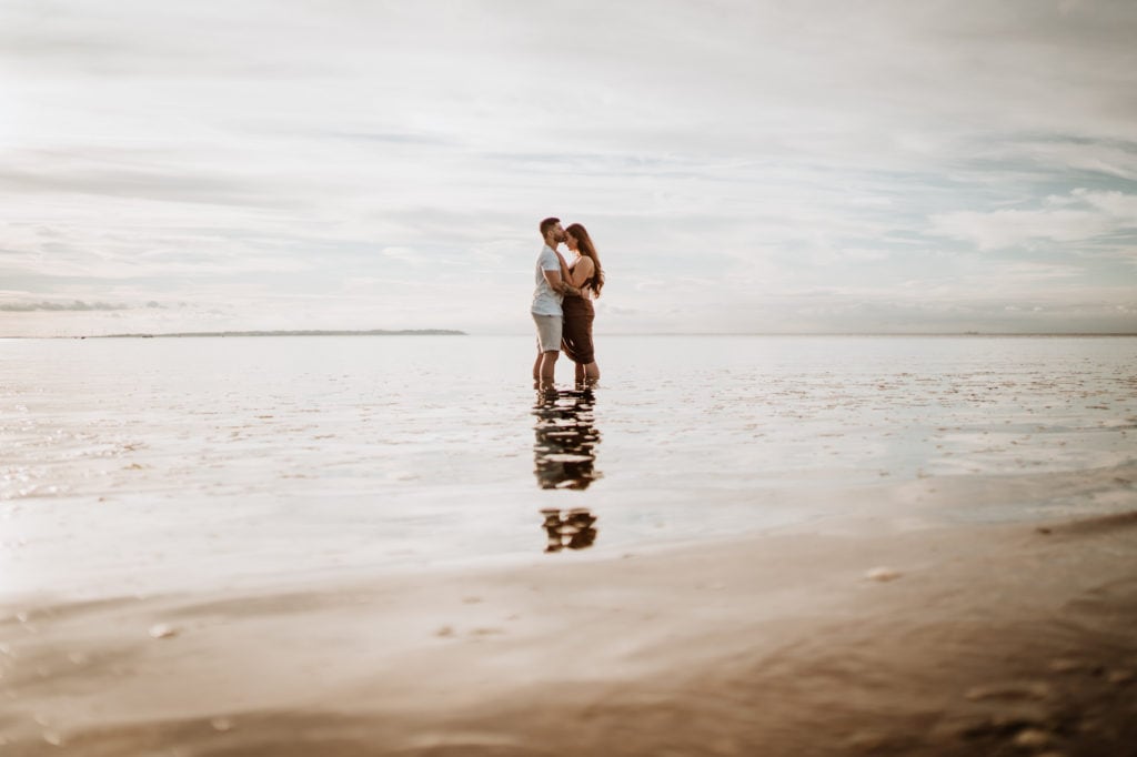 Couple stood together kissing in the sea at Whitstable