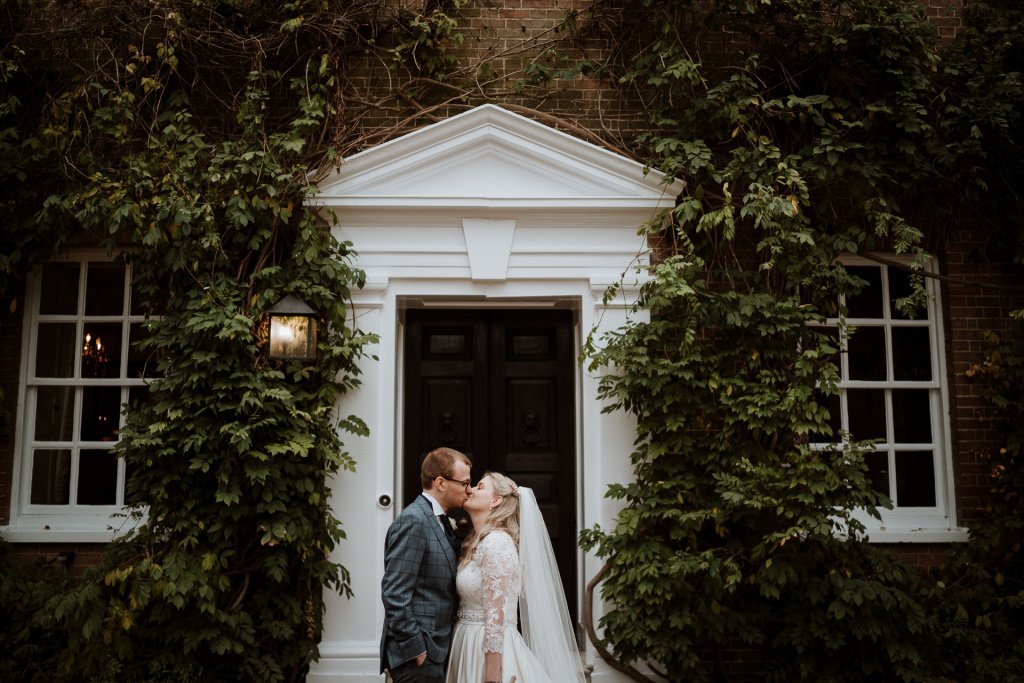 Bride and groom kissing on the doorstep pf Sprivers Mansion, their Kent Wedding venue