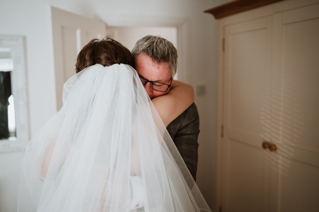 Bride in embrace with her father before her wedding