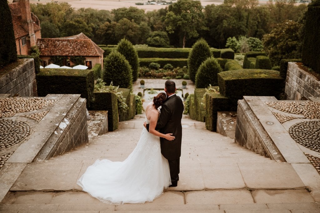 Bride and Groom with arms around one another looking out over the kent countryside