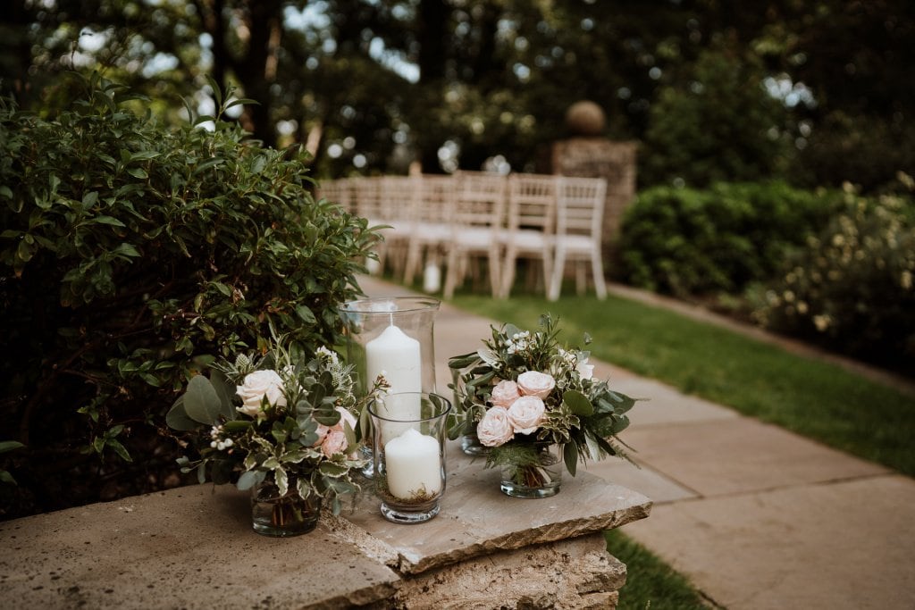 Stunning wedding flowers in subtle colour palette with candles dressing open air ceremony venue