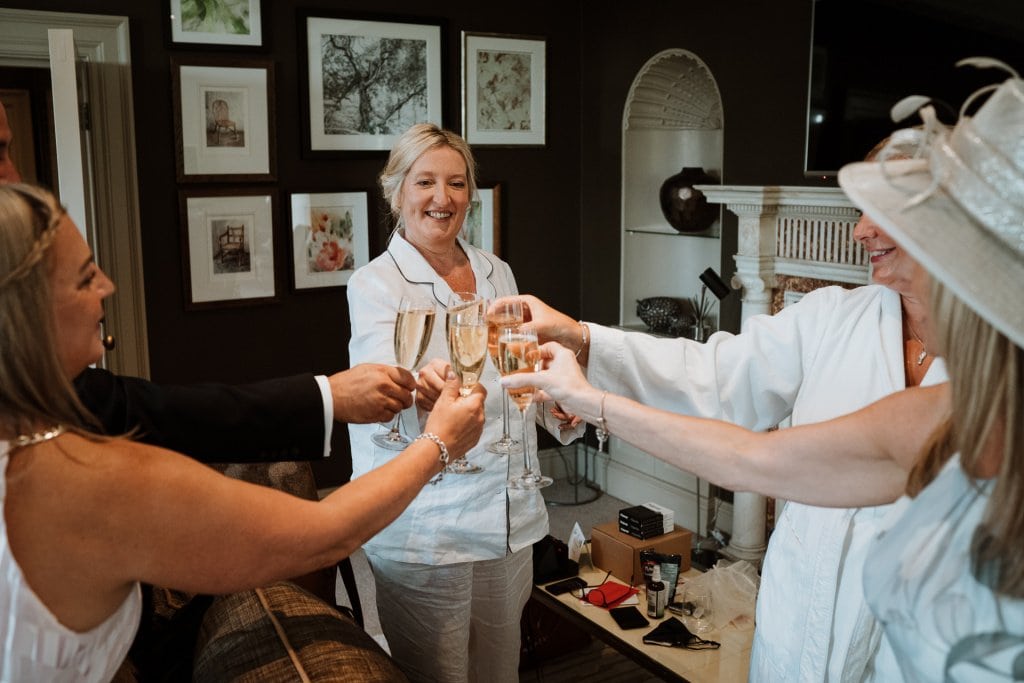 Bride and bridesmaids toast with champagne in bridal suite of Foxhill Manor