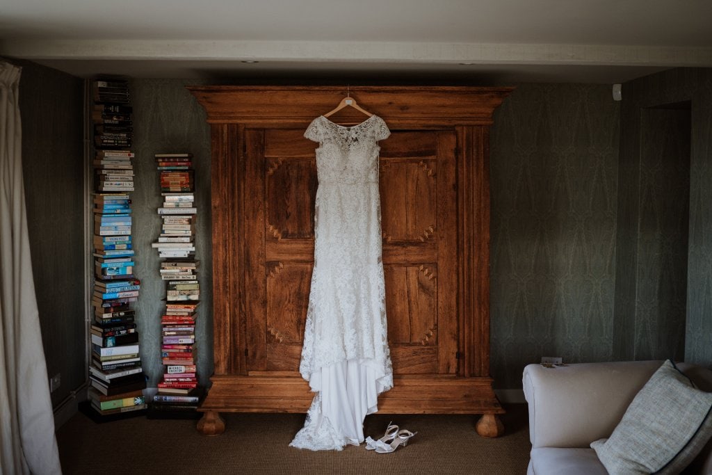 White lace wedding dress and bridal shoes displayed beautifully against dark wardrobe