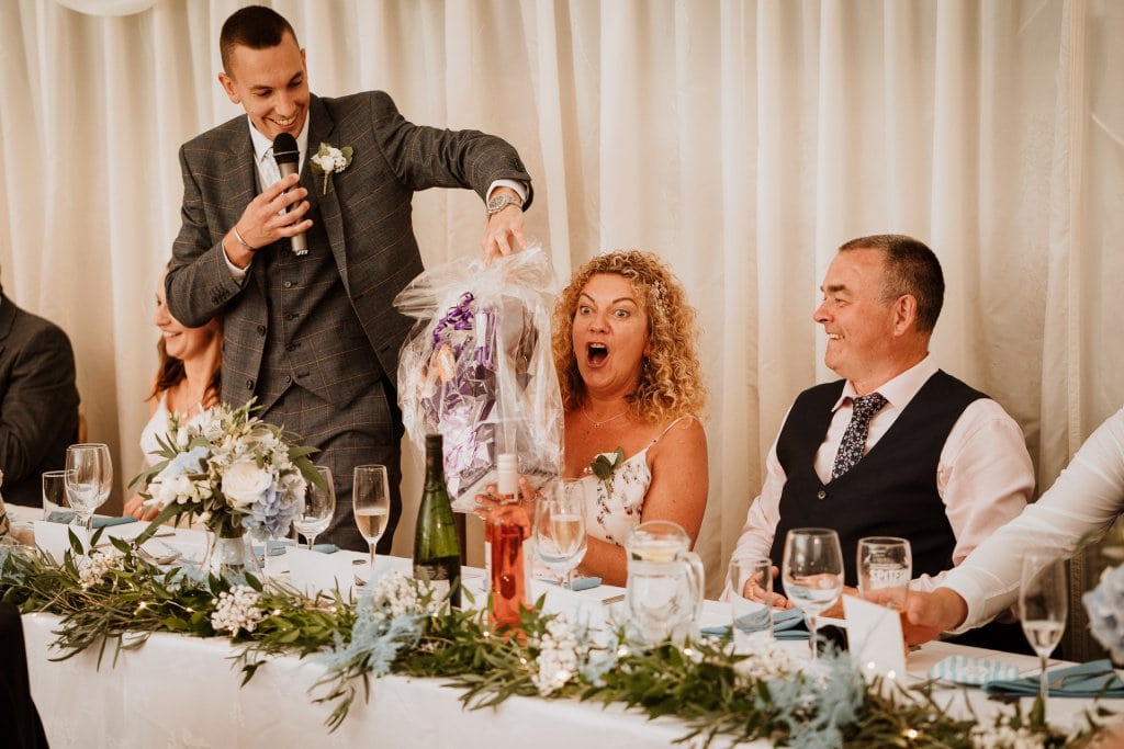 Grooms mother with surprised expression as she is given chocolate hamper