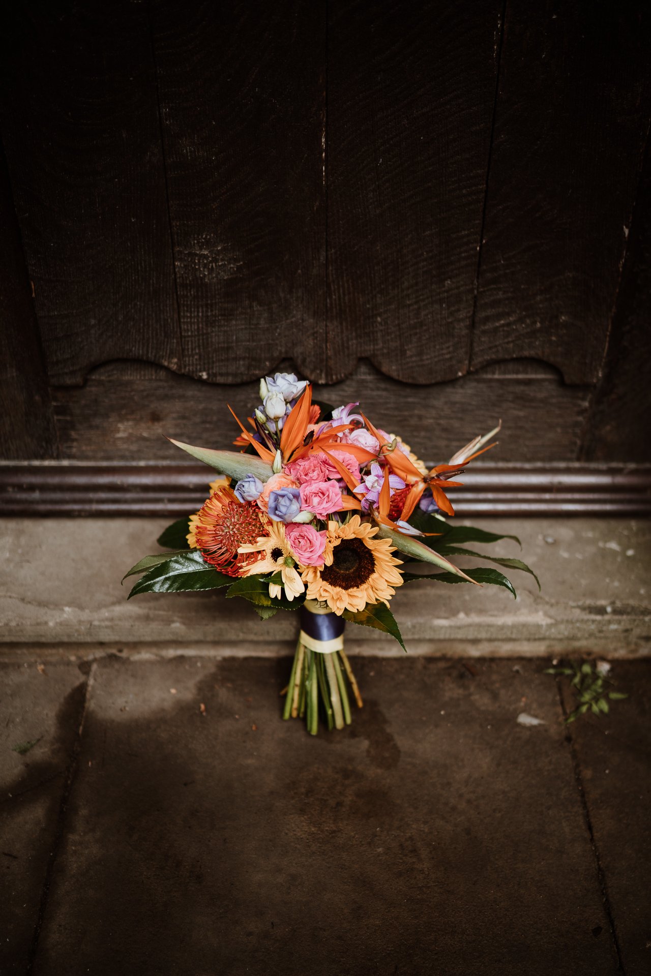 Bridal bouquet of bright, colourful exotic flowers resting against door step