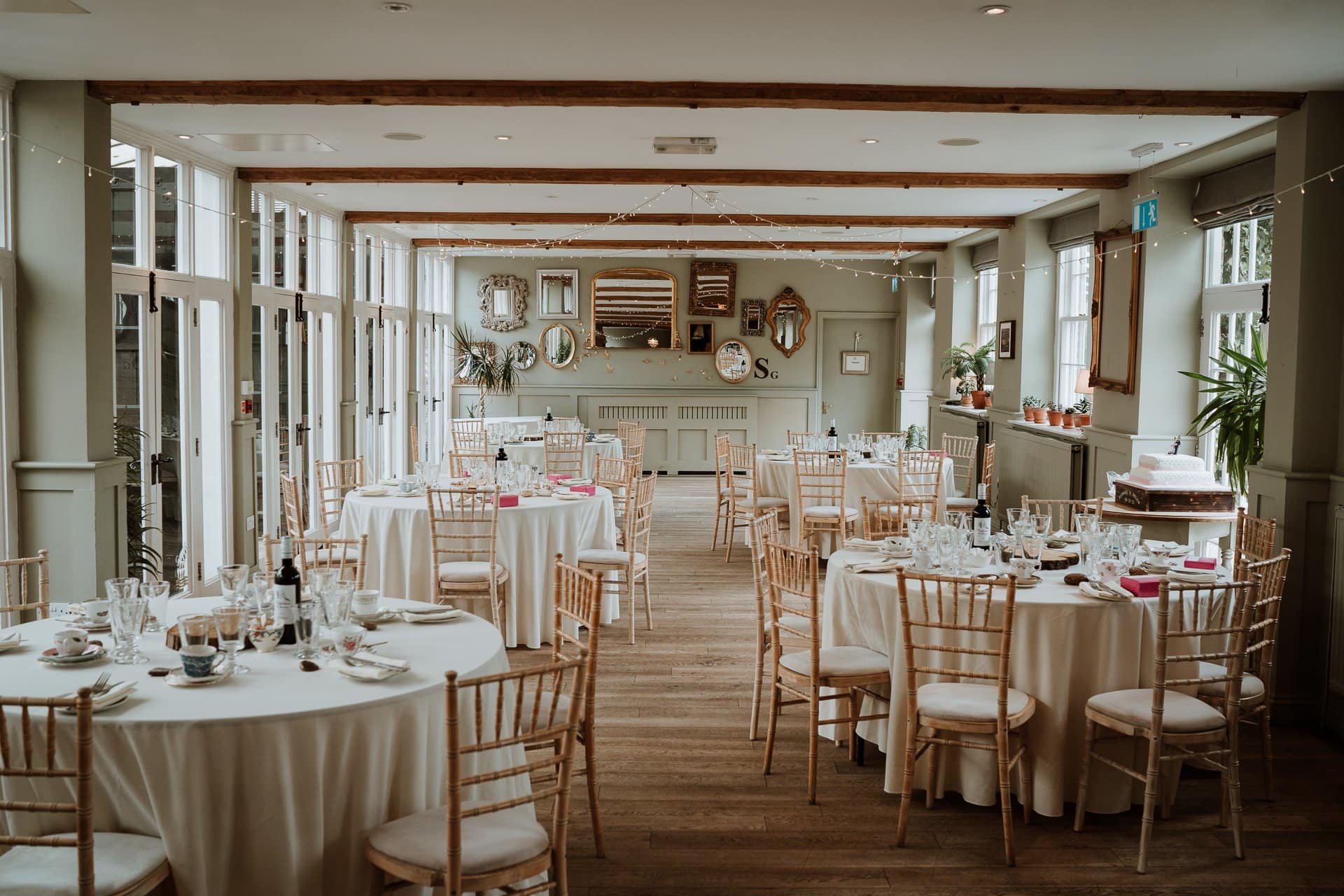 The coach house in the Secret Garden, dressed for seated wedding breakfast with round tables and pink floral centre pieces