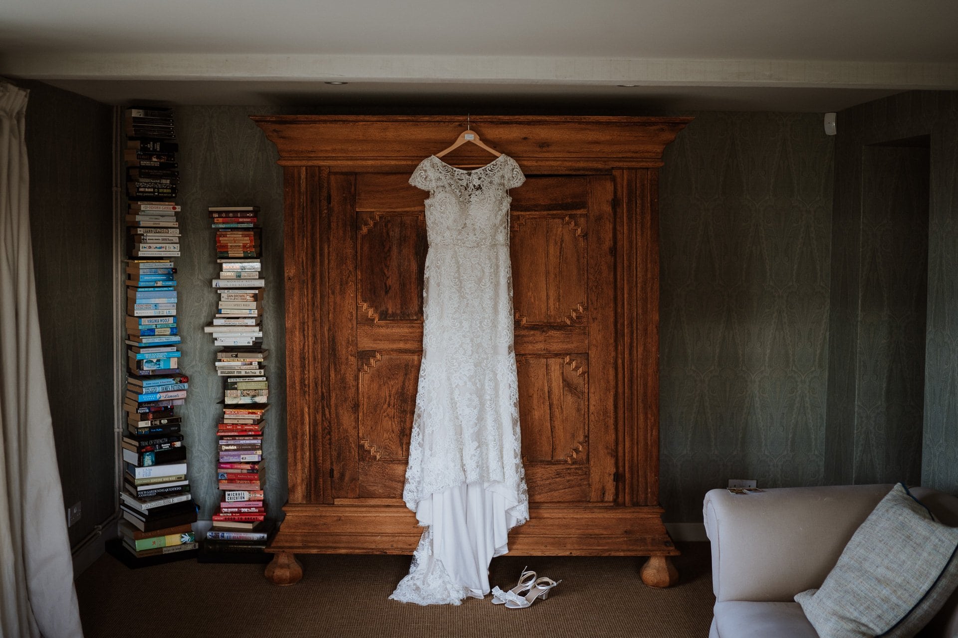 Beautiful lace brides dress hung on large dark wood wardrobe