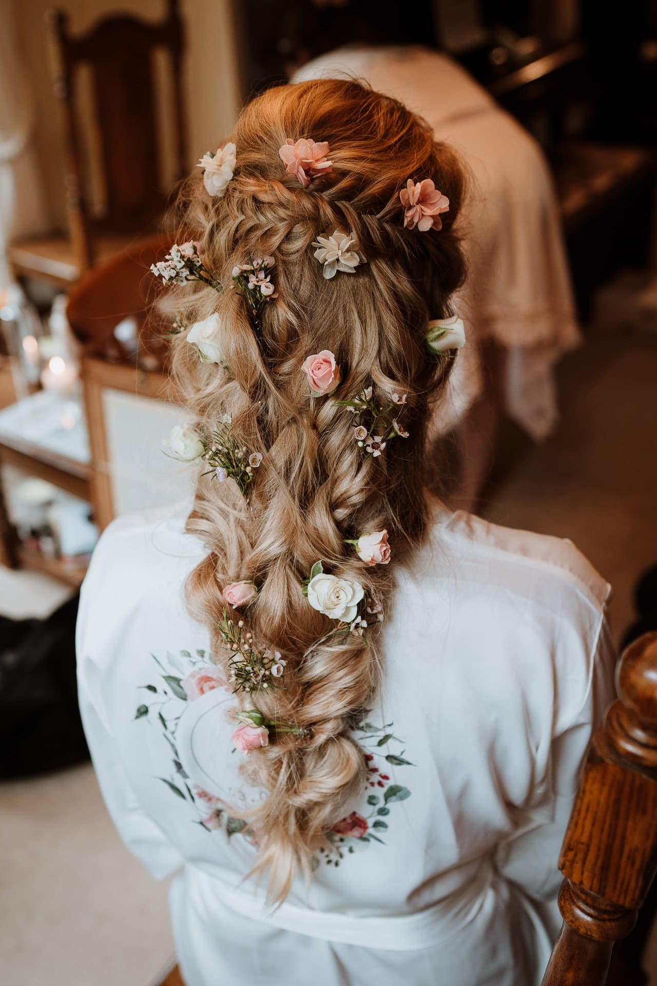 Brides loosely braided hair adorned with pink and white roses