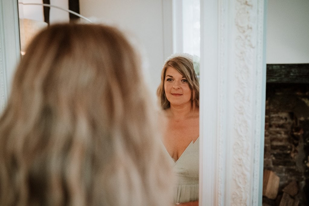 Bride looking at her reflection in the bridal suite mirror during bridal preparations