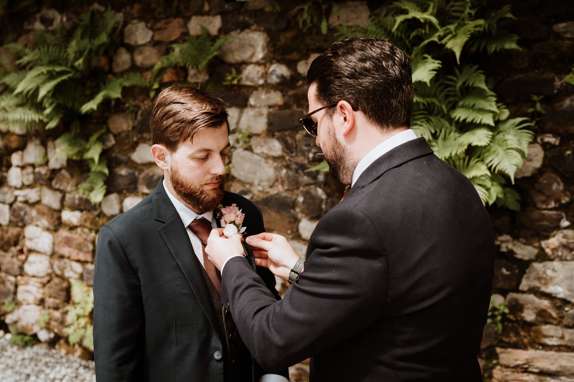 Best man helping the groom put on his button hole