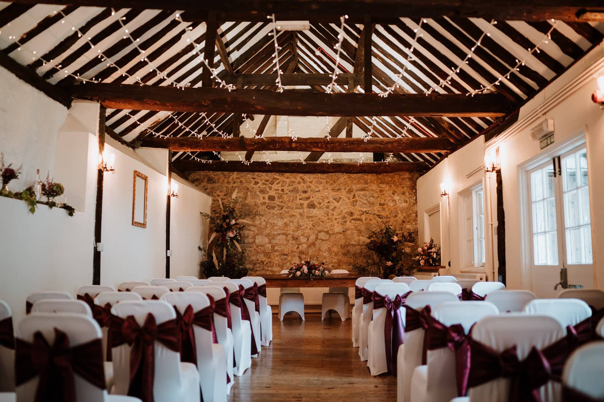 The Buttery wedding ceremony room at The Bull Hotel set for a ceremony with white char covers and burgundy sashes.