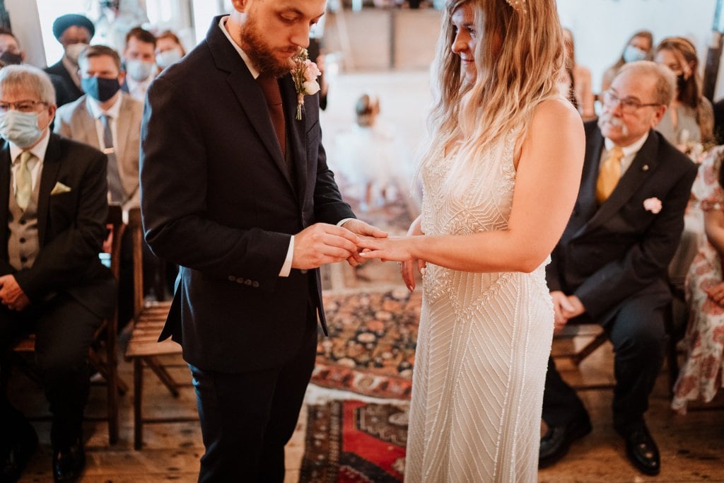 Groom placing a wedding ring on the brides hand during their kent wedding ceremony