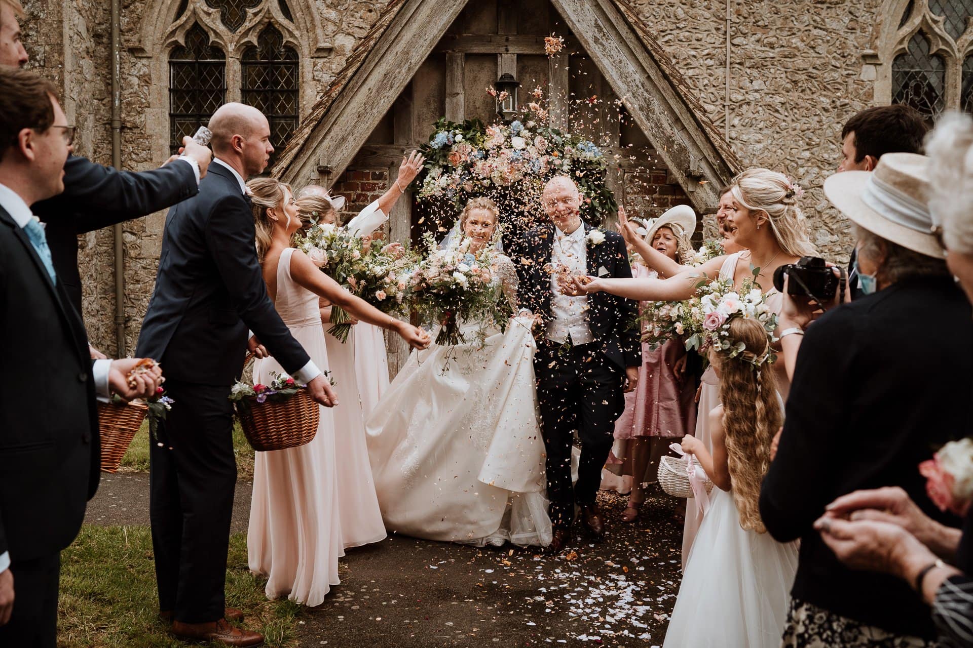 Bride and Groom being showered with confetti as they exit their church wedding ceremony