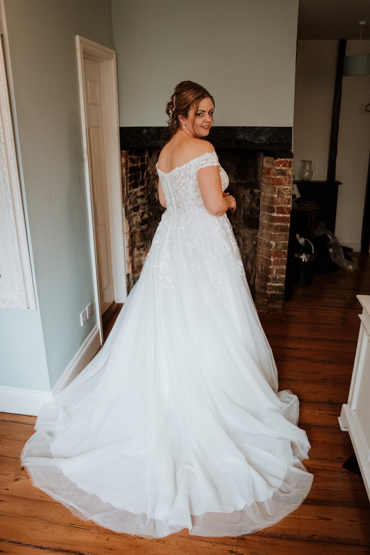 Bride wearing of the shoulder wedding dress in the bridal suite of The Bull Hotel