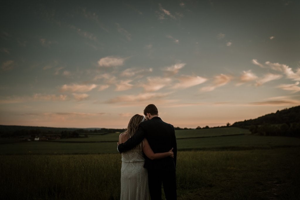 Bride and Groom holding each other over looking the Kent countryside at sunset