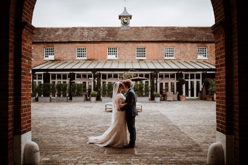 Bride and groom kiss with the backdrop of the Coach house at The Secret Garden