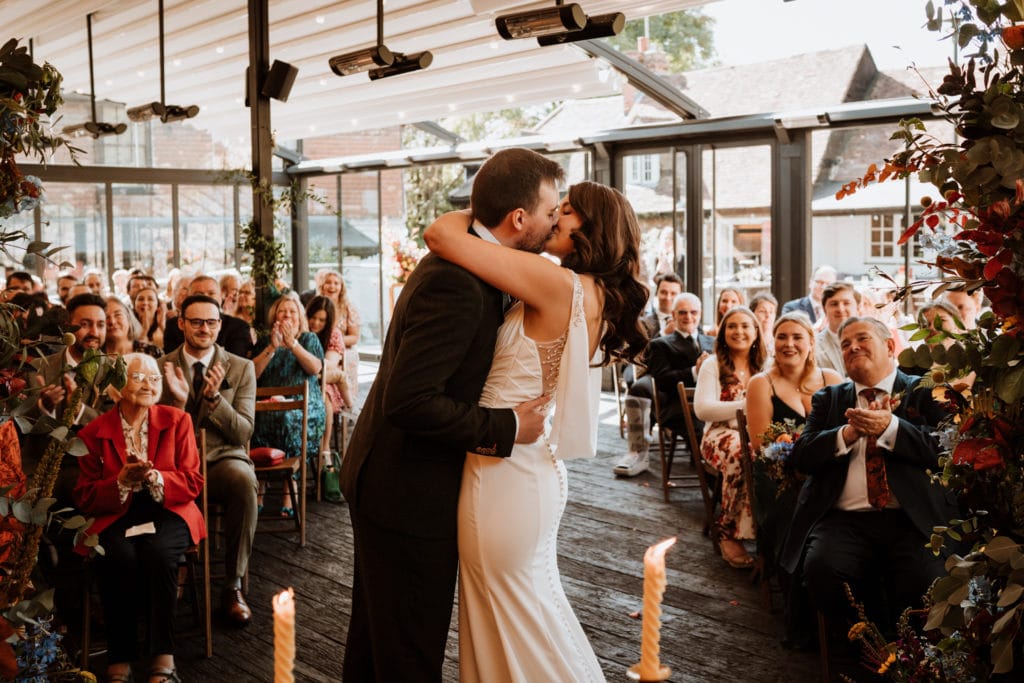 Bride and Groom share their first kiss as their guests look on 