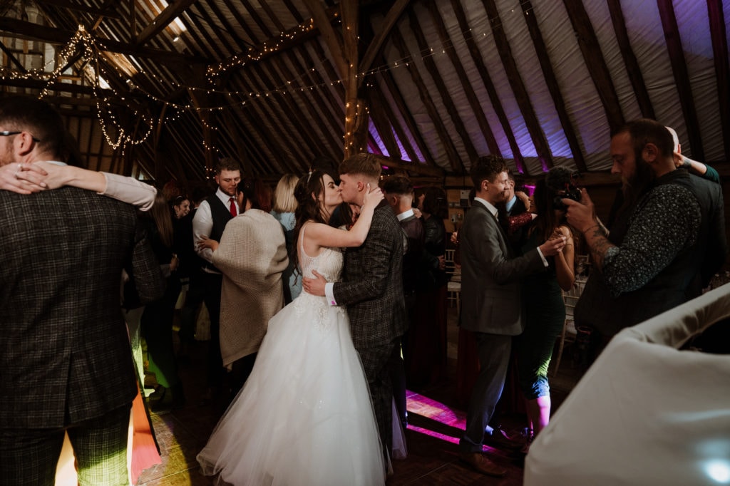 Bride and Groom kissing during their dance on crowded dance floor
