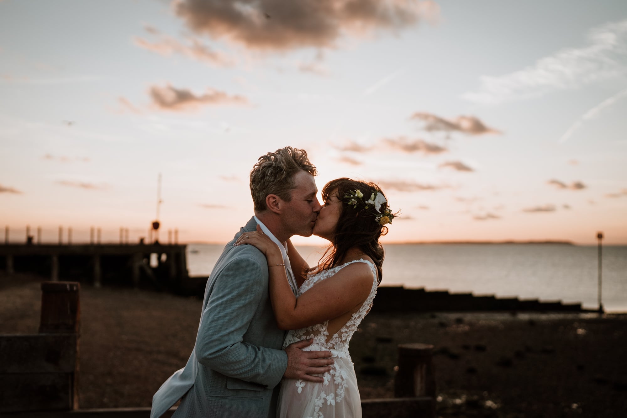 Relaxed Bride and Groom kiss on the beach at Whitstable with a sunset behind them