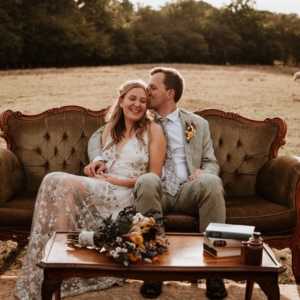 Bride and groom kissing on green sofa in stunning farm setting