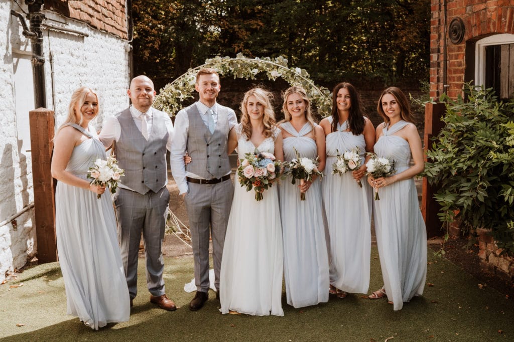 Bride and groom with their bridesmaids in pale blue dresses in relaxed group shot