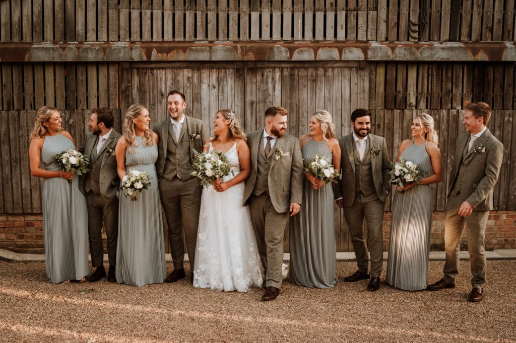 Bride and groom and their bridal party all laughing together in a relaxed group