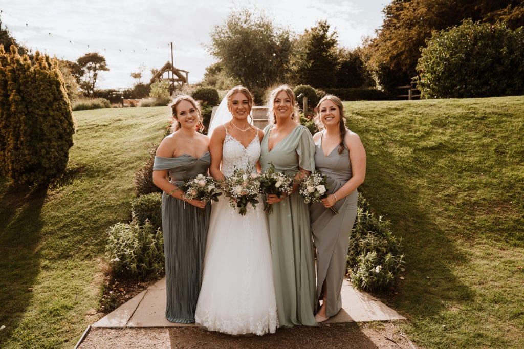 Bride and bridesmaids in pale green dresses in group shot at Reach Court Farm Kent Wedding venue