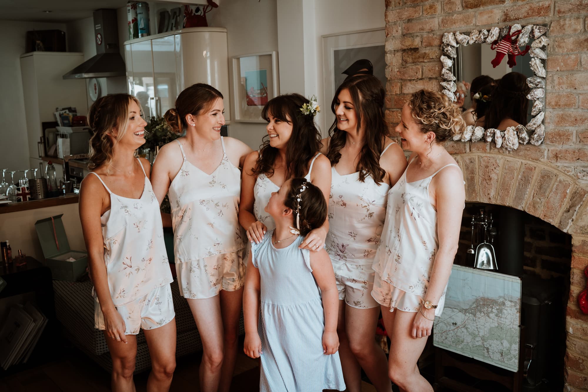 Bride and her bridesmaids in matching pyjamas looking relaxed and smiling at each other