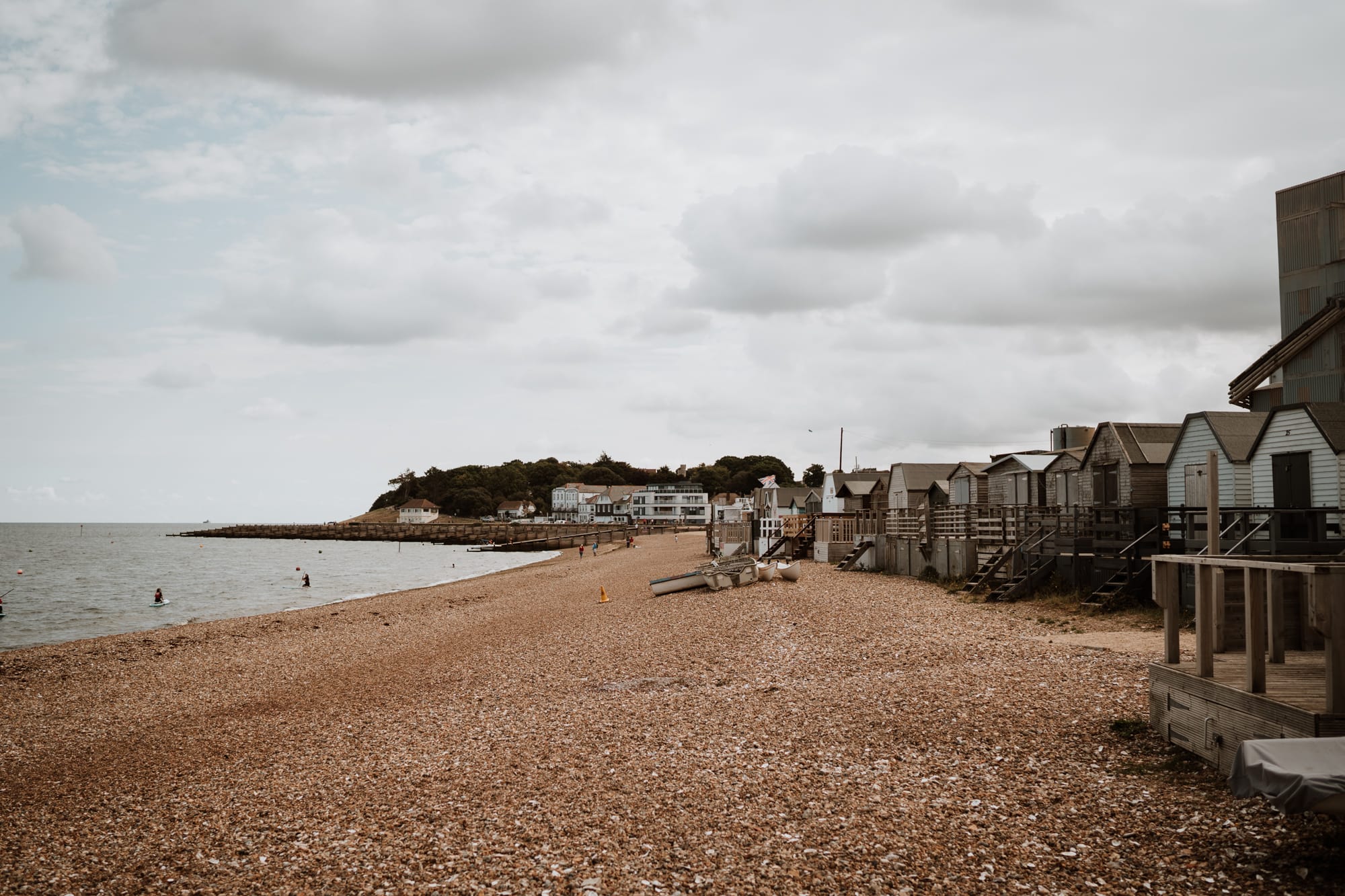 View along Whitstable Beach with white cloud and beach huts