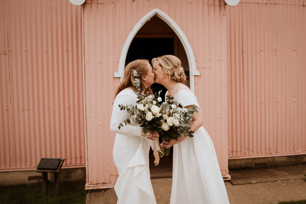 Natural wedding photos of the couples kissing outside of their wedding venue