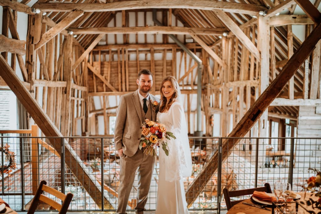 The couple standing inside of The Oak Barn at Frame Farm in Benenden which is a wedding venue in Kent