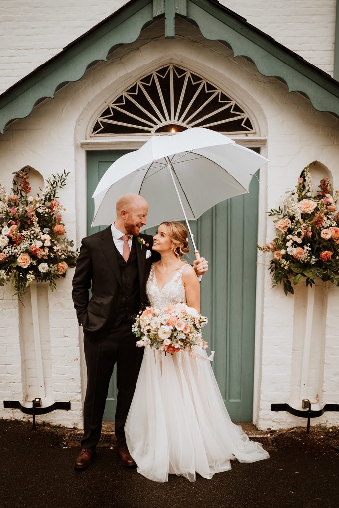 Couple under a white umbrella on a rainy wedding day in Kent